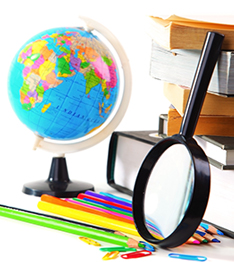 Magnifying glass, globe, colored pencils, paperclips and stacked books